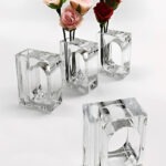 Four transparent glass vases hold pink and red artificial roses. The elegant design highlights floral arrangements, perfect for decorative purposes.