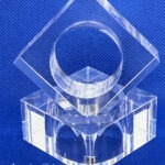 Clear acrylic sculpture featuring a circular and diamond shape, designed for decorative purposes on a blue background.